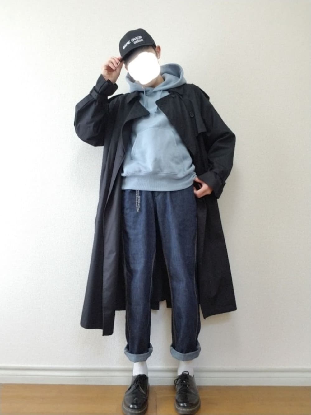 ブルー系のパーカー、ブラック系のトレンチコート、ブラック系のデニムパンツを着用したメンズの春コーディネートの1枚目の写真