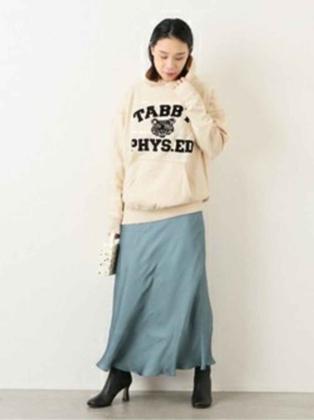 ベージュ系のパーカー、ブラック系のブーツを着用したレディースの冬コーディネートの1枚目の写真