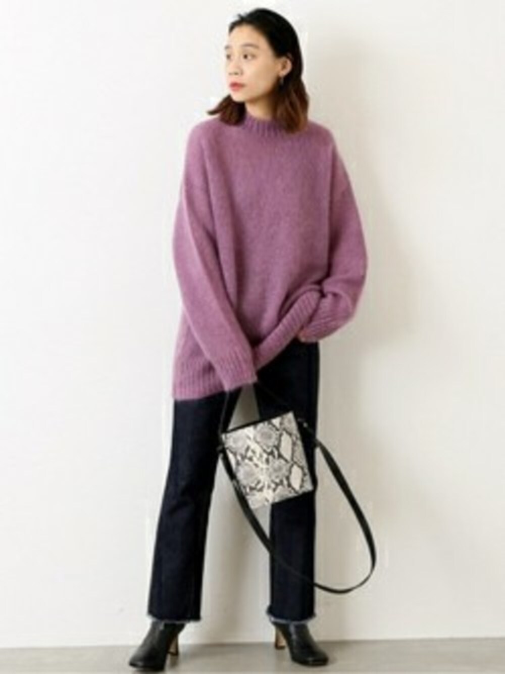 パープル系のニット/セーター、ブルー系のデニムパンツを着用したレディースの冬コーディネートの1枚目の写真