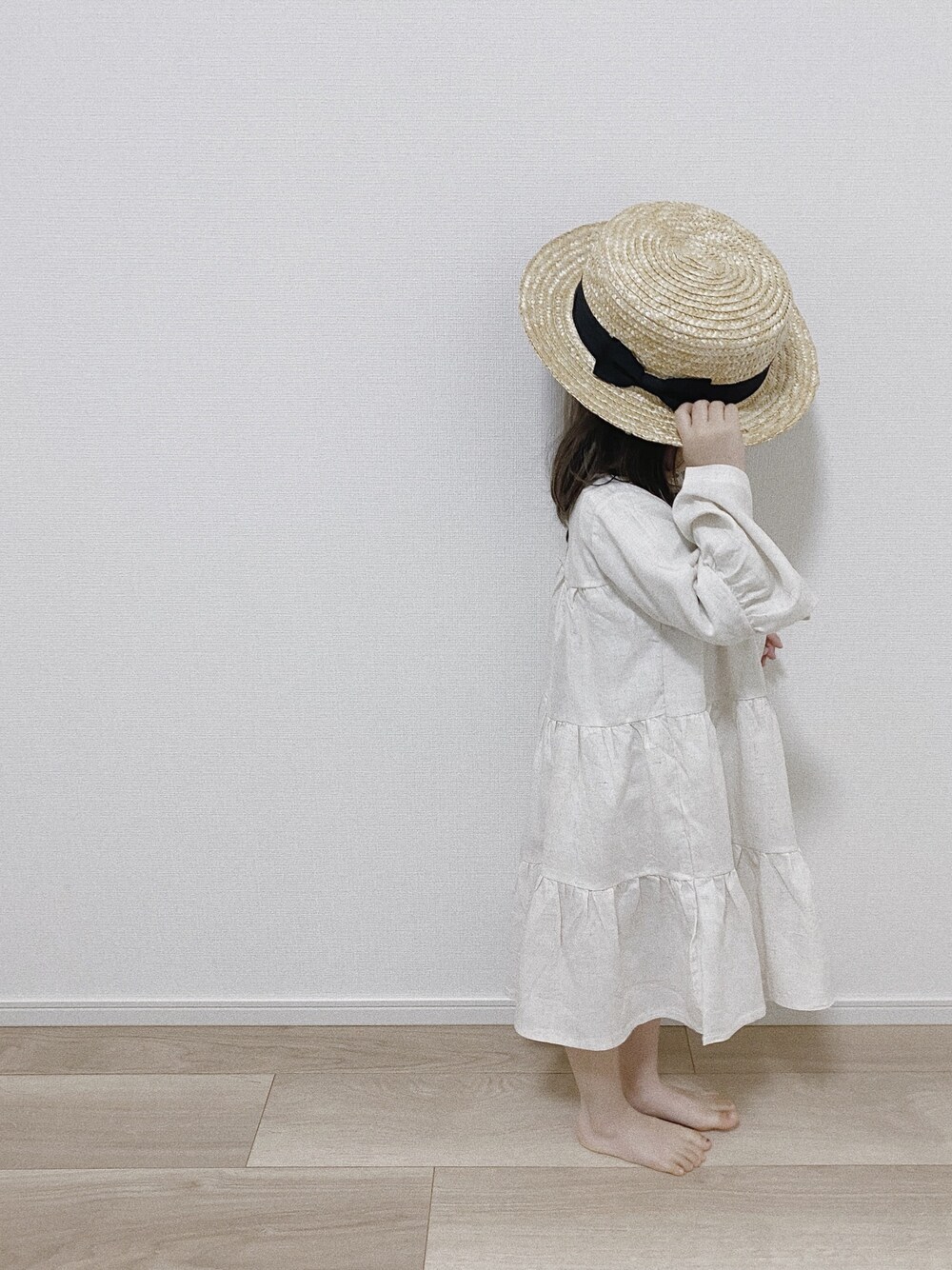 ホワイト系のワンピース、ベージュ系の帽子を着用したキッズの春コーディネートの1枚目の写真