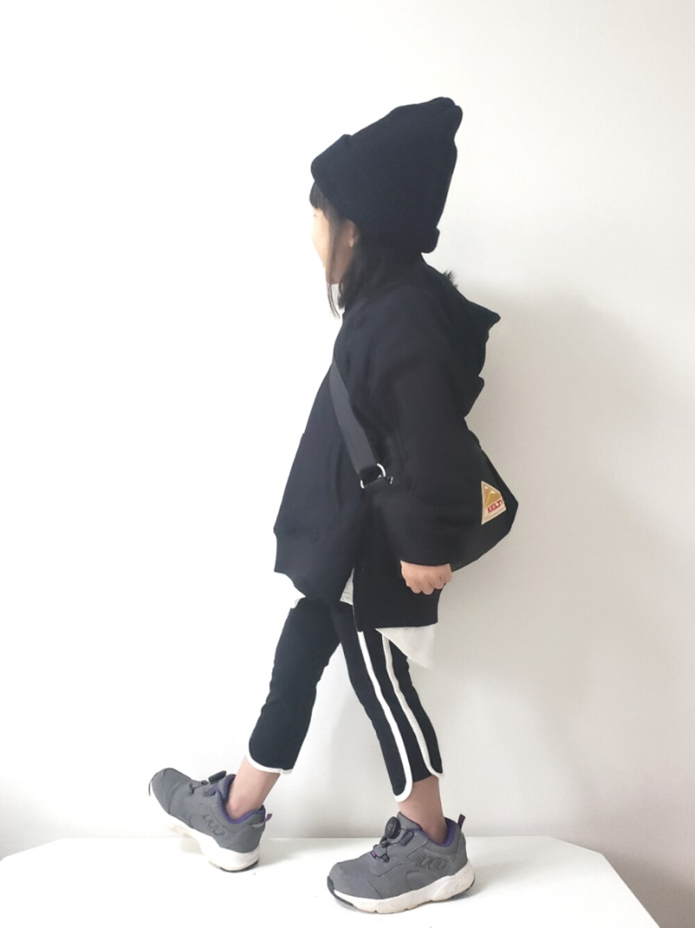 ブラック系のパンツ、グレー系のスニーカー、ブラック系のショルダーバッグを着用したキッズの冬コーディネートの1枚目の写真