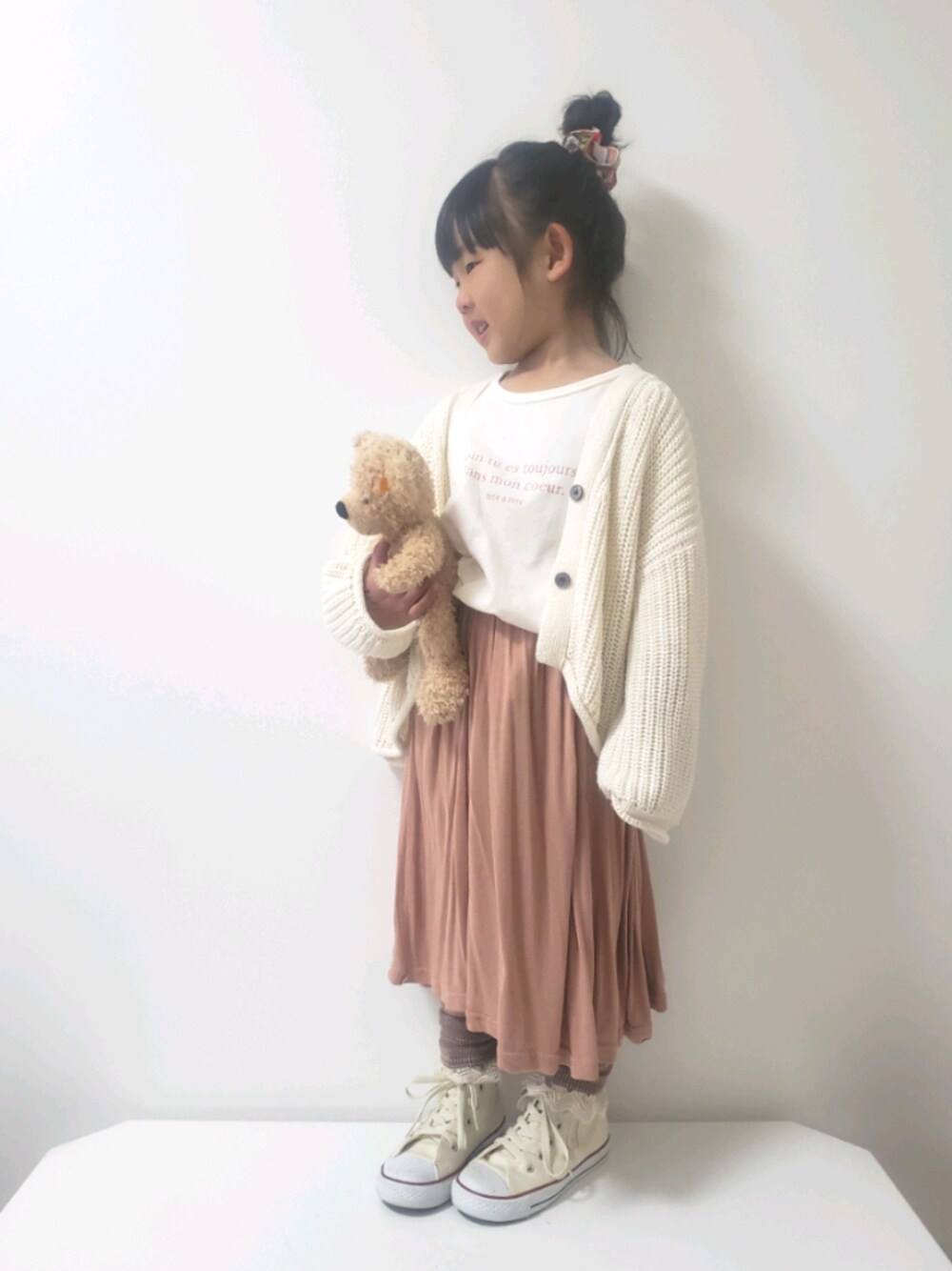 ピンク系のスカート、ホワイト系のスニーカー、ホワイト系のカーディガン/ボレロを着用したキッズの春コーディネートの1枚目の写真