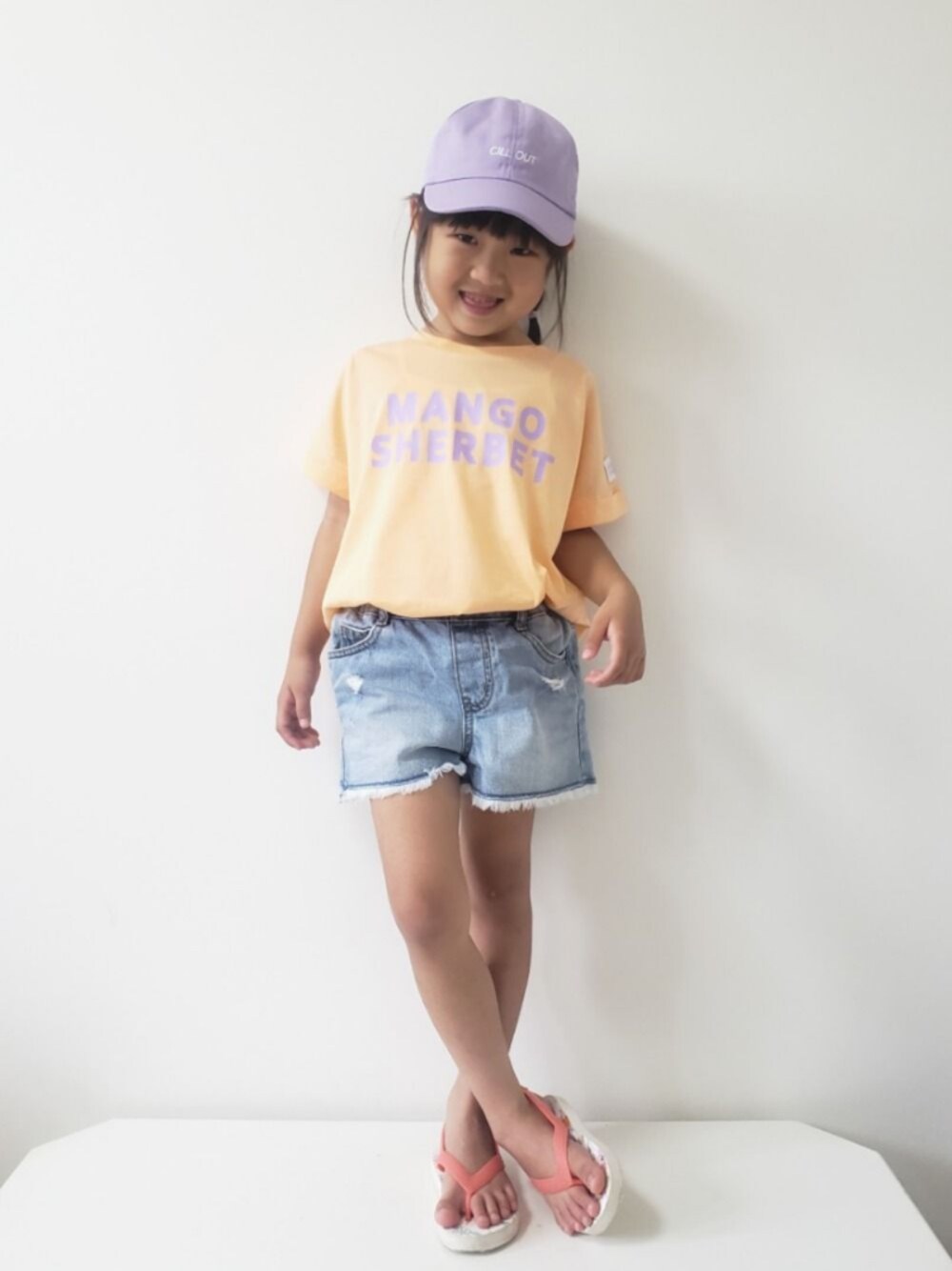オレンジ系のTシャツ/カットソー、ブルー系のデニムパンツ、ピンク系のビーチサンダルを着用したキッズの夏コーディネートの1枚目の写真