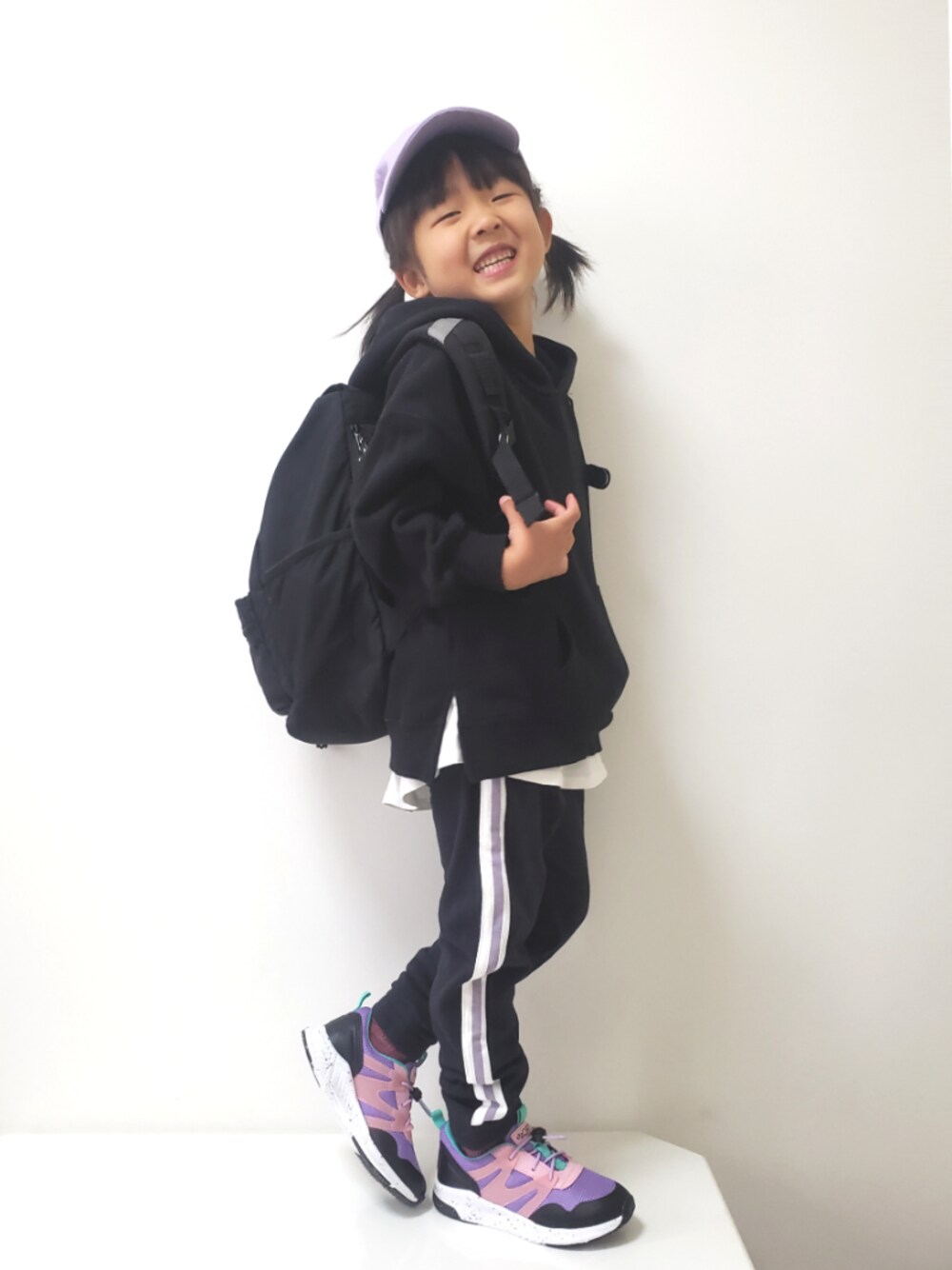 ブラック系のスウェットパンツ、ブラック系のパーカー、ホワイト系のスニーカーを着用したキッズの秋コーディネートの1枚目の写真