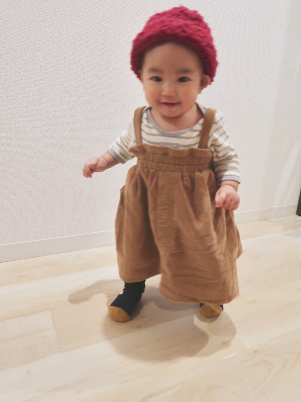 ベージュ系のワンピース、レッド系のニットキャップ/ビーニー、グレー系のロンパースを着用したキッズの秋コーディネートの1枚目の写真