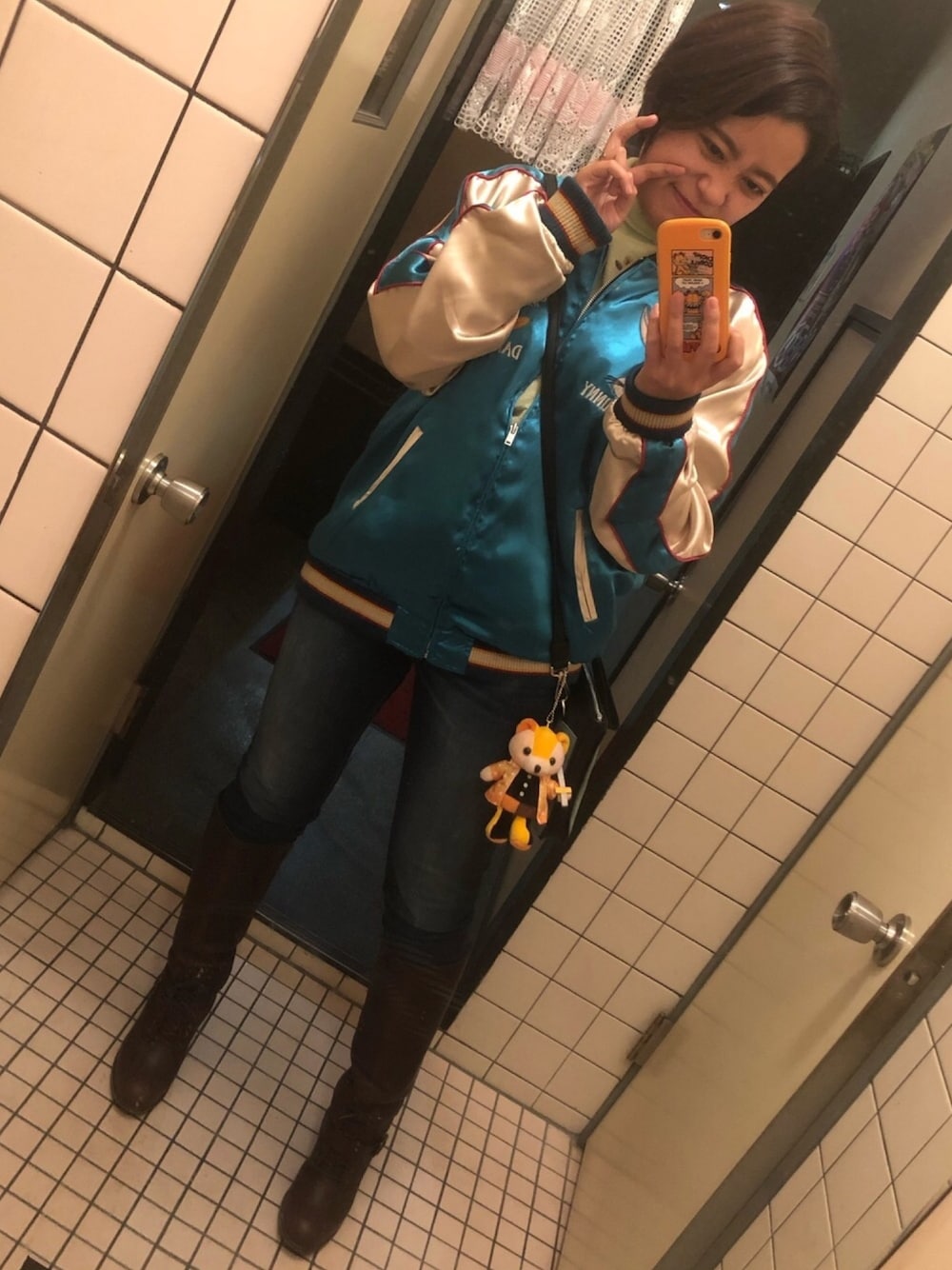 グリーン系のニット/セーター、ブルー系のスカジャン、ブルー系のショルダーバッグを着用したレディースの秋コーディネートの1枚目の写真