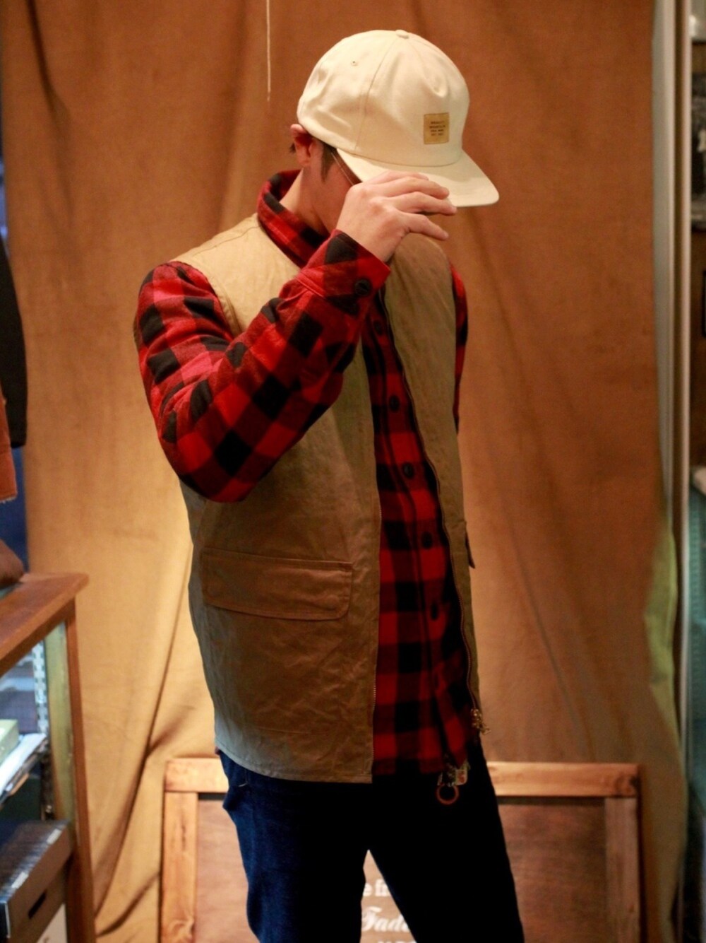 ベージュ系のベスト、レッド系のシャツ/ブラウス、ブルー系のデニムパンツを着用したメンズの秋コーディネートの1枚目の写真