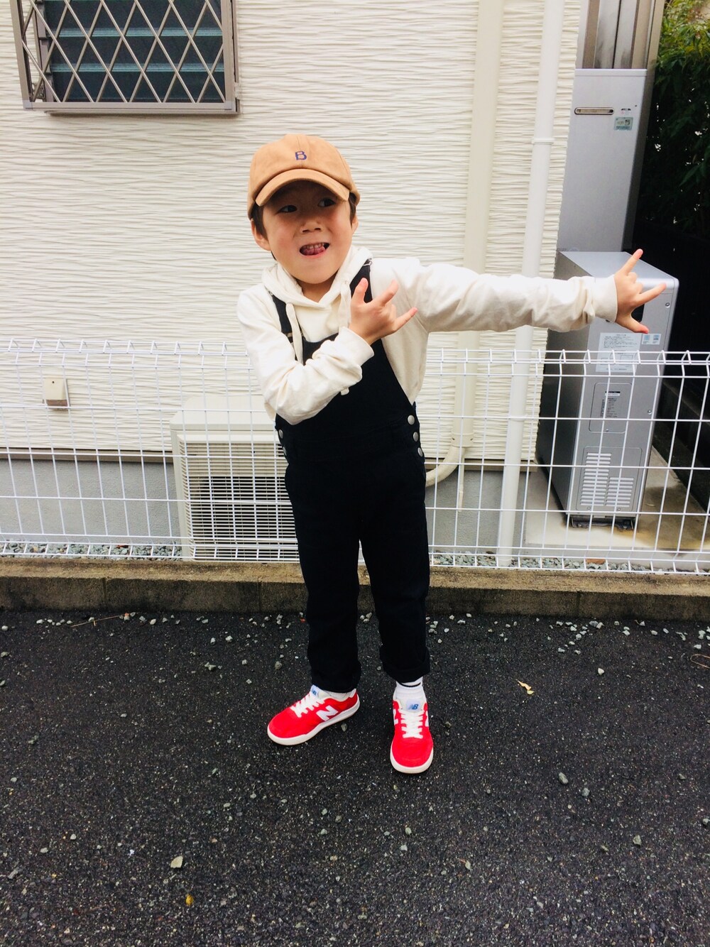 ホワイト系のトップス、ブラック系のサロペット/オーバーオール、レッド系のスニーカーを着用したキッズの冬コーディネートの1枚目の写真