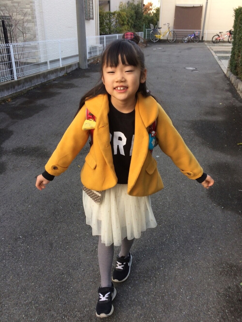 ブラック系のスウェット、ホワイト系のスカート、ブラック系のスニーカーを着用したキッズの冬コーディネートの1枚目の写真
