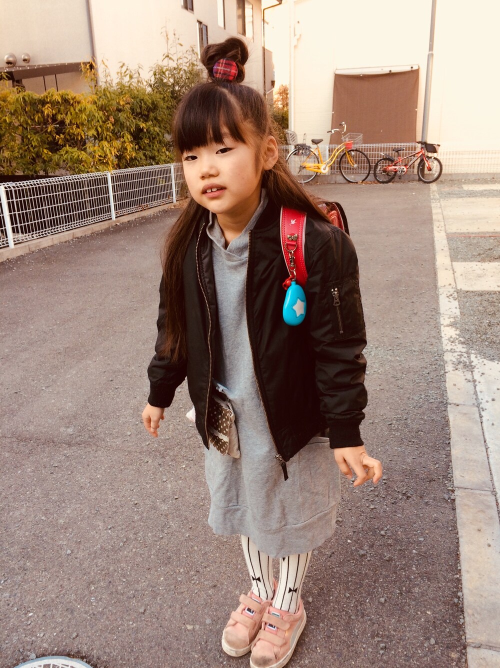 グレー系のワンピース、ピンク系のスニーカー、ブラック系のジャケット/アウターを着用したキッズの冬コーディネートの1枚目の写真