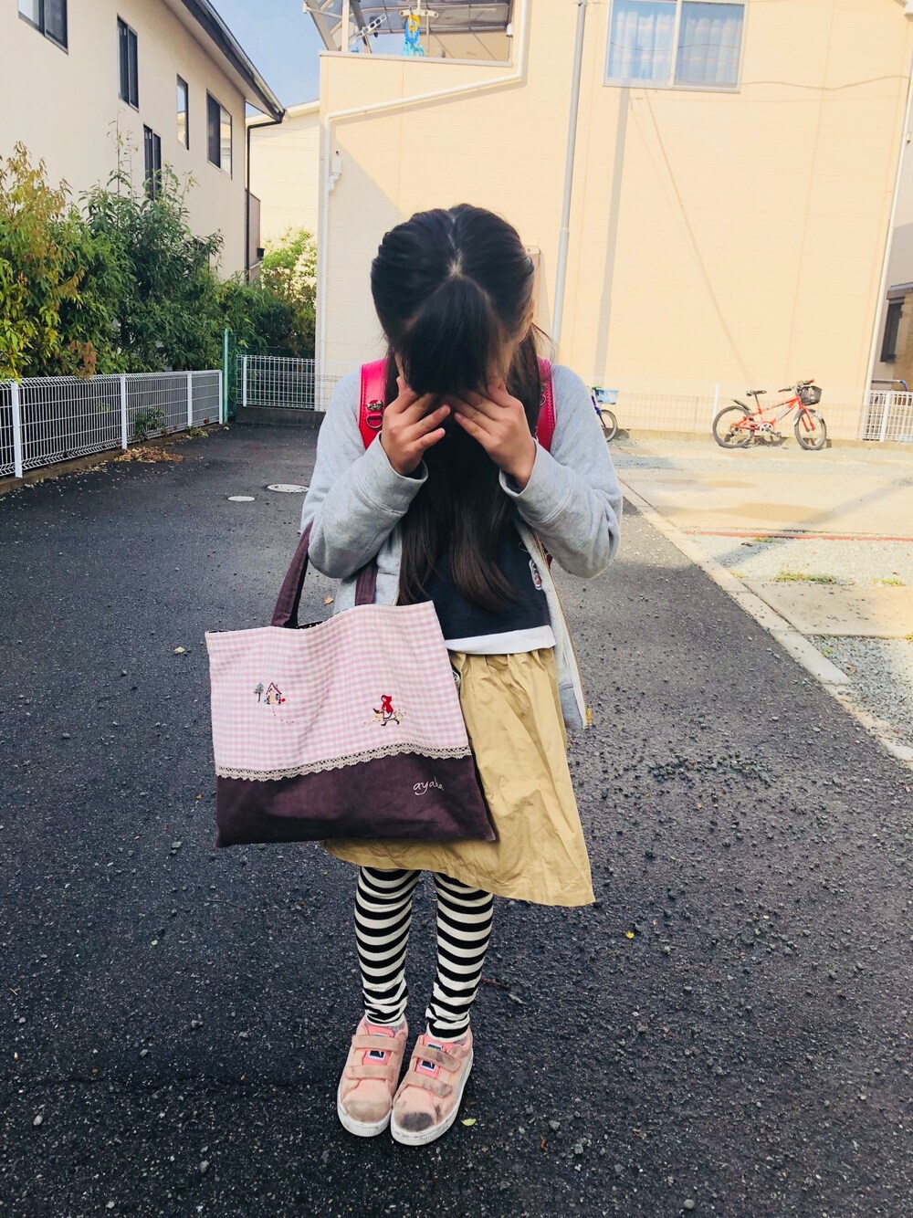 グレー系のワンピース、ピンク系のスニーカー、グレー系のパーカーを着用したキッズの春コーディネートの1枚目の写真