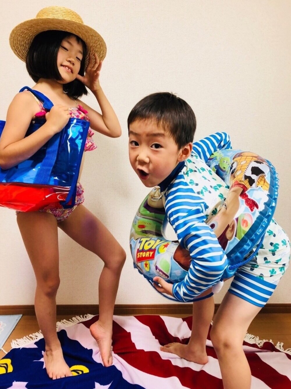ブルー系のトートバッグ、ホワイト系の水着、ホワイト系のラッシュガードを着用したキッズの夏コーディネートの1枚目の写真