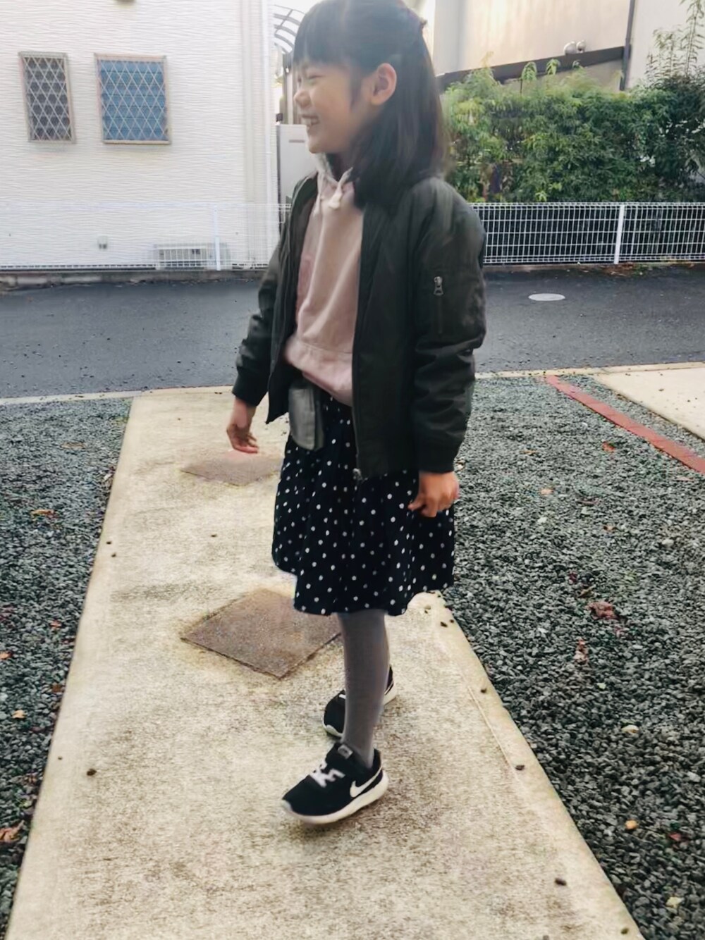 ブラック系のスニーカー、ブルー系のスカート、ピンク系のパーカーを着用したキッズの冬コーディネートの1枚目の写真