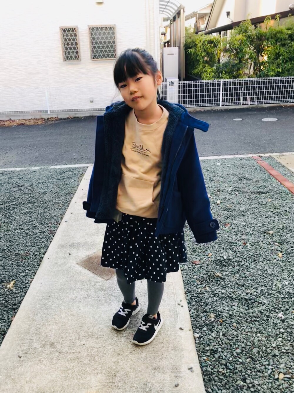 ベージュ系のスウェット、ブルー系のスカート、ブラック系のスニーカーを着用したキッズの冬コーディネートの1枚目の写真