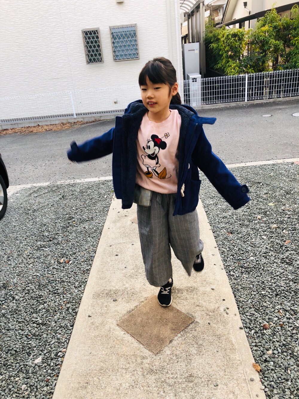 ピンク系のトップス、グレー系のパンツ、ブラック系のスニーカーを着用したキッズの冬コーディネートの1枚目の写真
