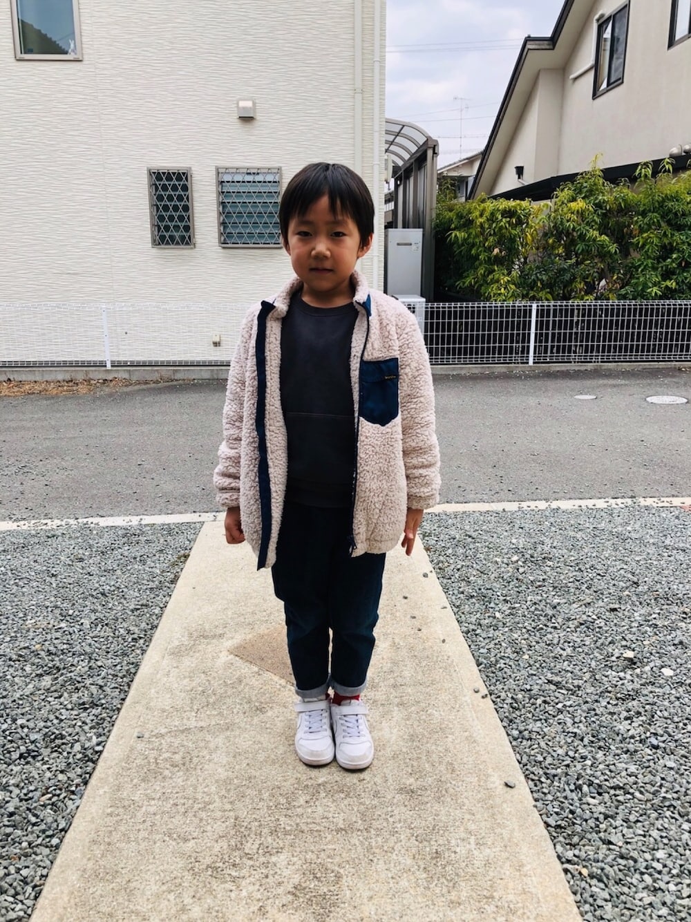 グレー系のスウェット、ブルー系のデニムパンツ、ホワイト系のスニーカーを着用したキッズの冬コーディネートの1枚目の写真