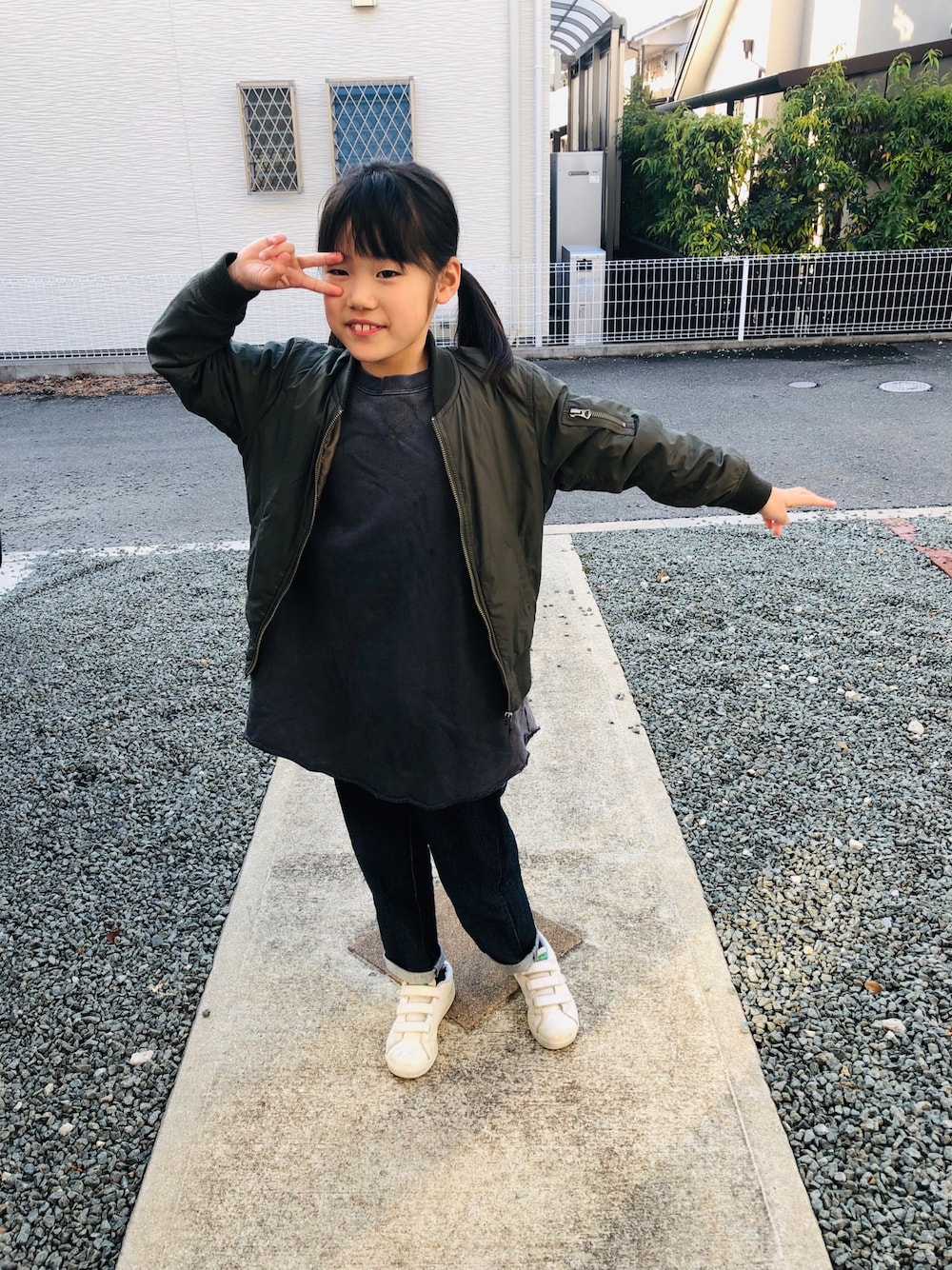グレー系のワンピース、ブルー系のデニムパンツ、ホワイト系のスニーカーを着用したキッズの春コーディネートの1枚目の写真