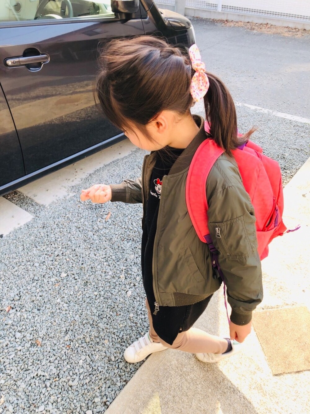 ブラック系のワンピース、ピンク系のバックパック/リュック、ホワイト系のスニーカーを着用したキッズの春コーディネートの1枚目の写真