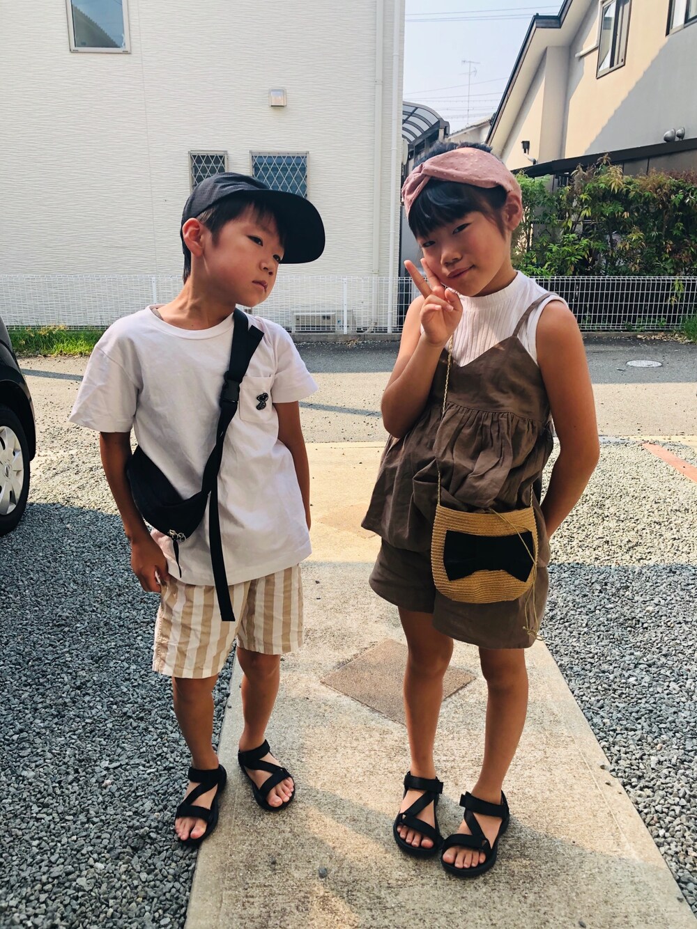 ホワイト系のタンクトップ、ブラウン系のオールインワン・サロペット、ブラック系のショルダーバッグを着用したキッズの夏コーディネートの1枚目の写真