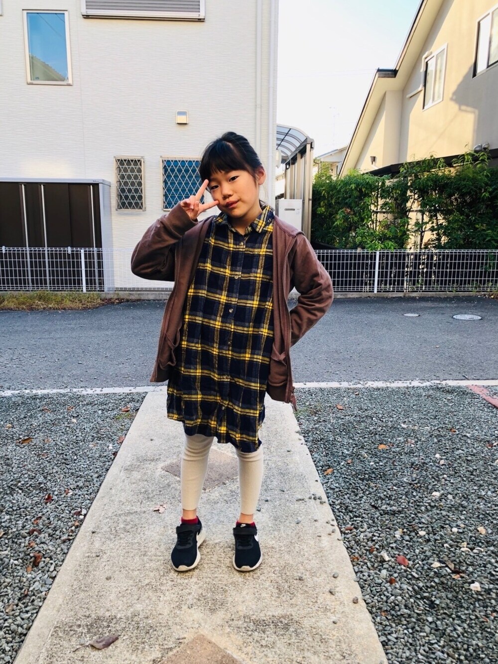 ブラウン系のパーカー、イエロー系のシャツワンピース、ブラック系のスニーカーを着用したキッズの秋コーディネートの1枚目の写真