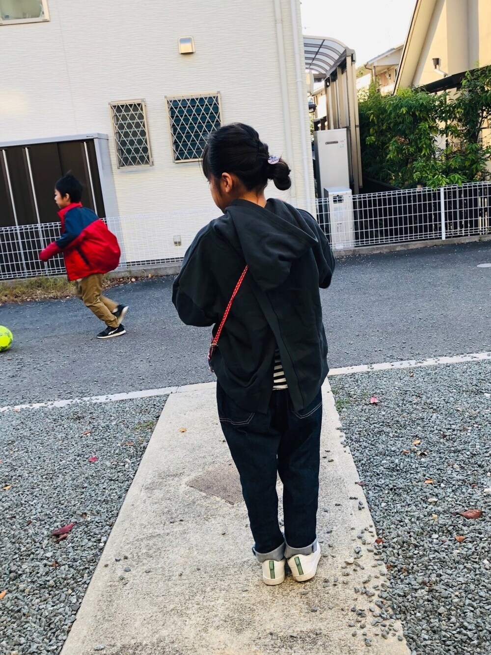 ブラック系のパーカー、ブルー系のデニムパンツ、ホワイト系のスニーカーを着用したキッズの秋コーディネートの1枚目の写真