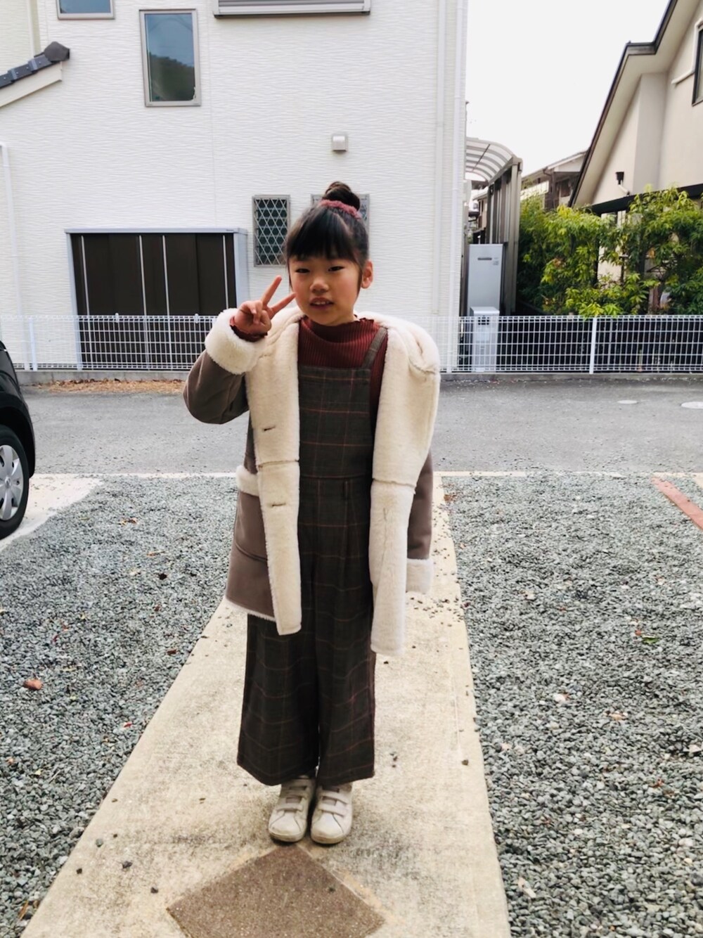 ブラウン系のデニムパンツ、グレー系のムートンコート、グリーン系のスニーカーを着用したキッズの冬コーディネートの1枚目の写真