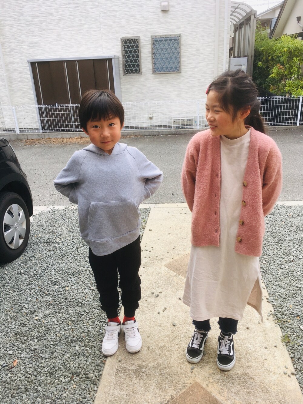 グレー系のパーカー、ホワイト系のスニーカー、ベージュ系のワンピースを着用したキッズの春コーディネートの1枚目の写真
