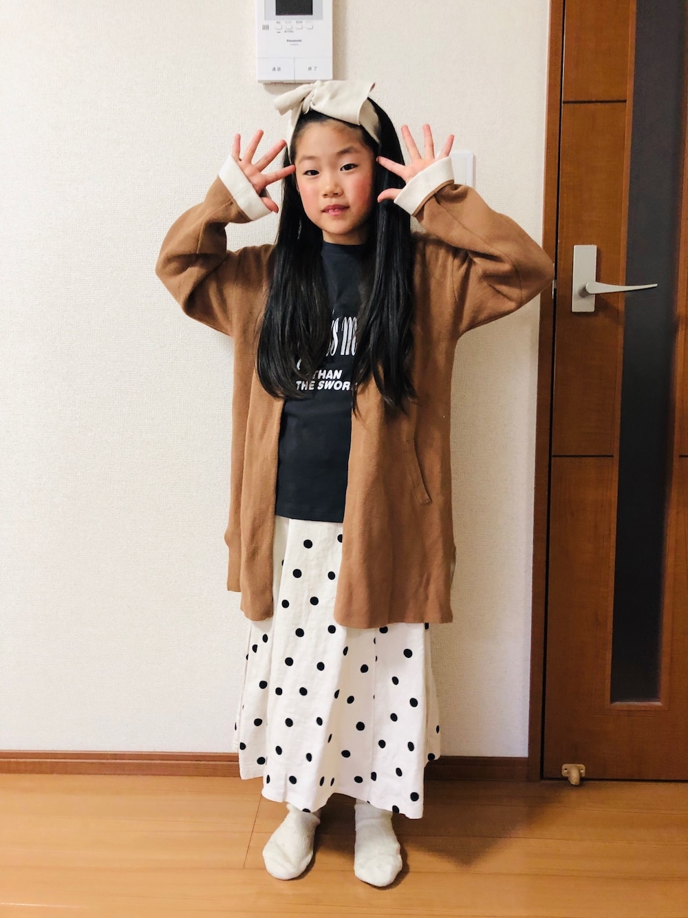 グレー系のTシャツ/カットソー、ブラウン系のカーディガン/ボレロ、ホワイト系のスカートを着用したキッズの春コーディネートの1枚目の写真