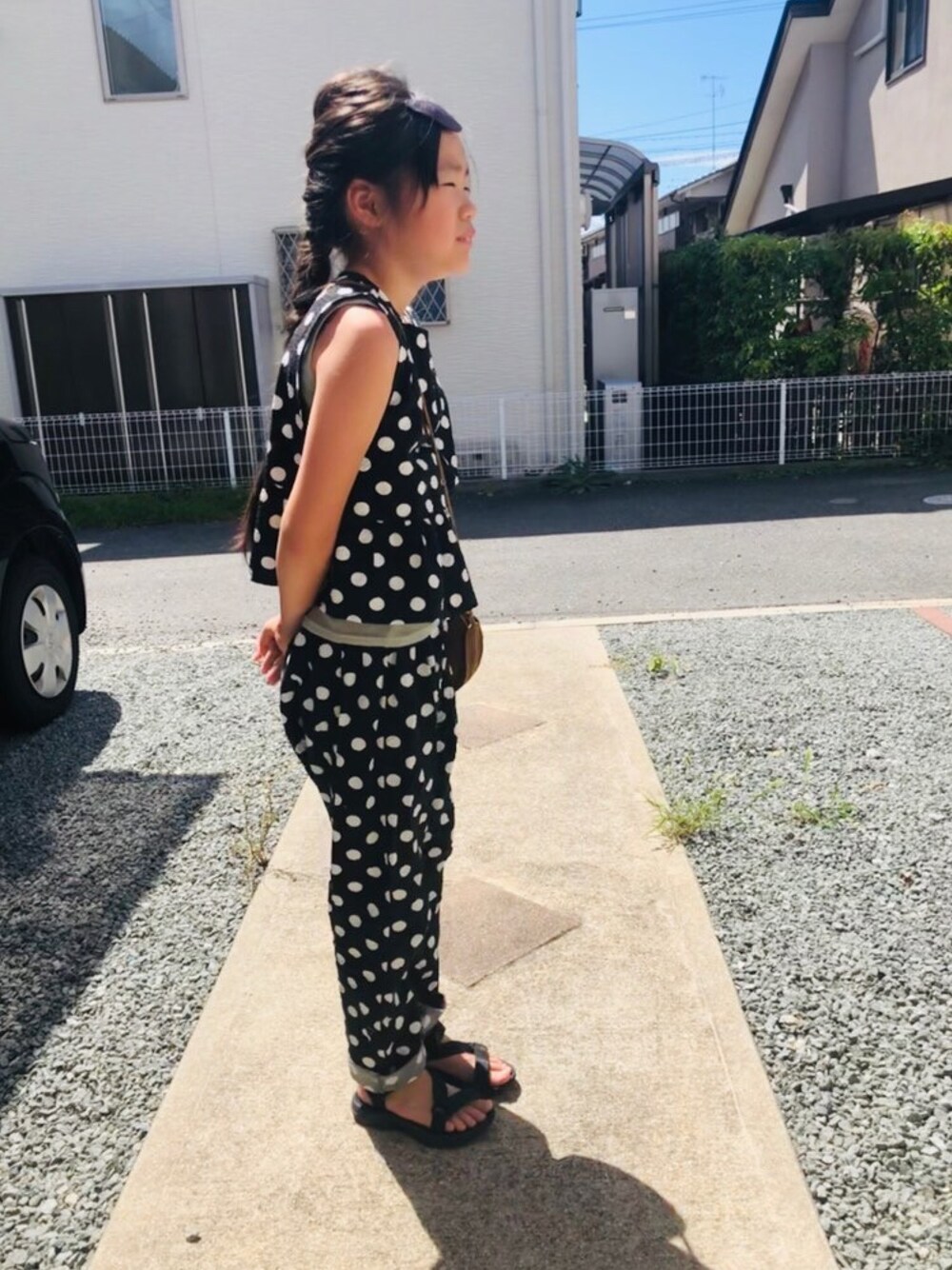 グリーン系のタンクトップ、ブラック系のサンダル、ブラウン系のショルダーバッグを着用したキッズの夏コーディネートの1枚目の写真