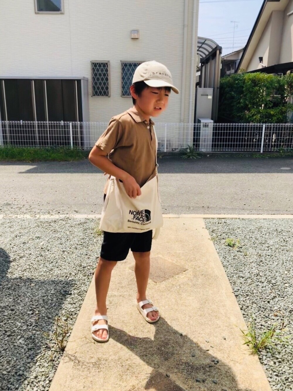 ベージュ系のポロシャツ、ブラック系のその他パンツ、ホワイト系のサンダルを着用したキッズの夏コーディネートの1枚目の写真