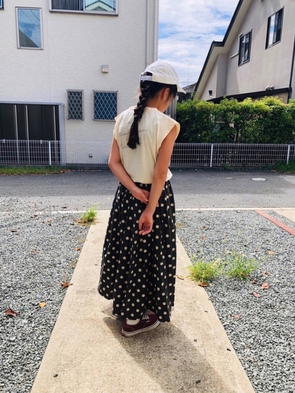 グレー系のスカート、ホワイト系のTシャツ/カットソー、レッド系のスニーカーを着用したキッズの秋コーディネートの1枚目の写真