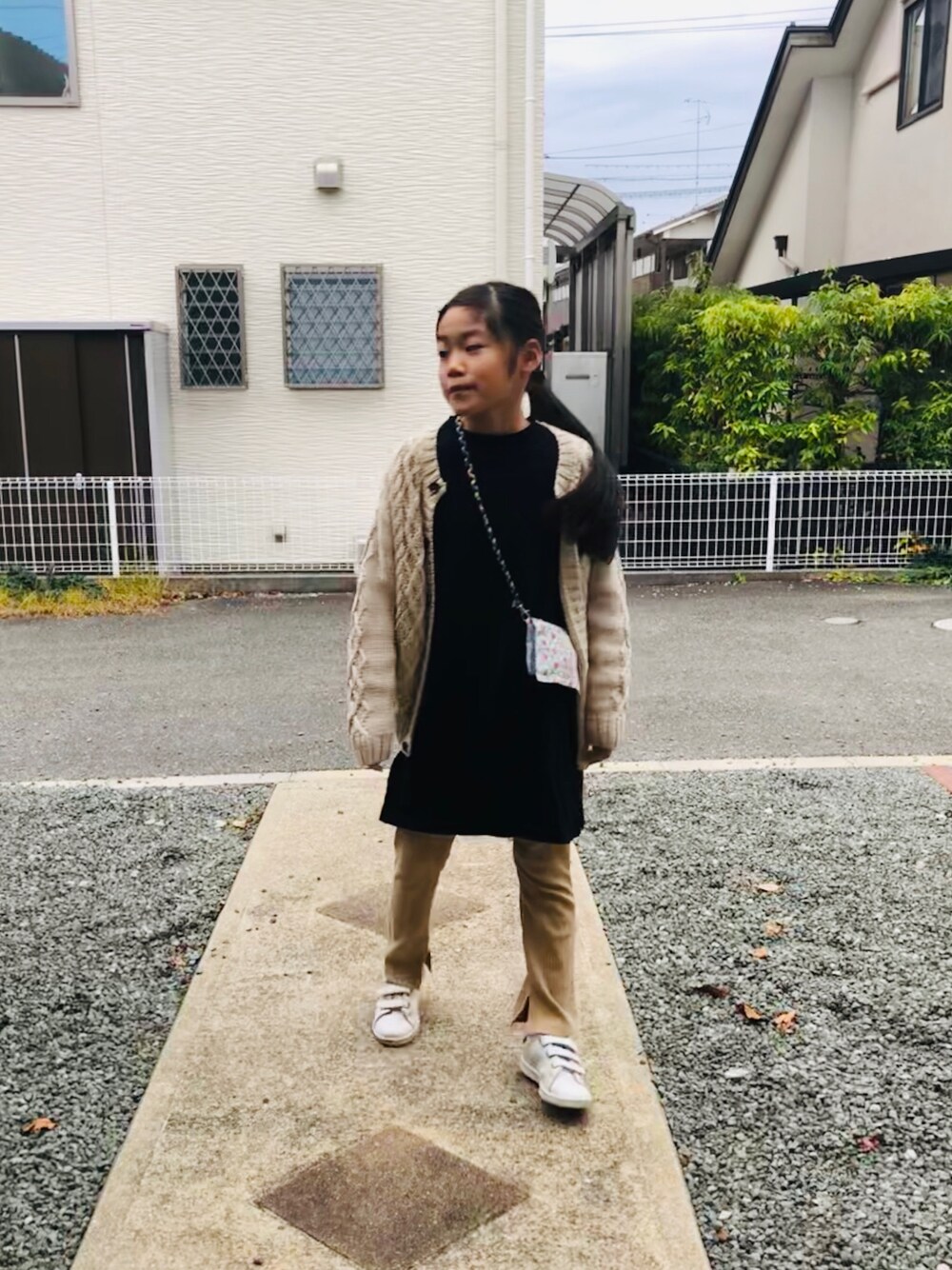 ブラック系のワンピース、ベージュ系のその他パンツ、ホワイト系のスニーカーを着用したキッズの秋コーディネートの1枚目の写真