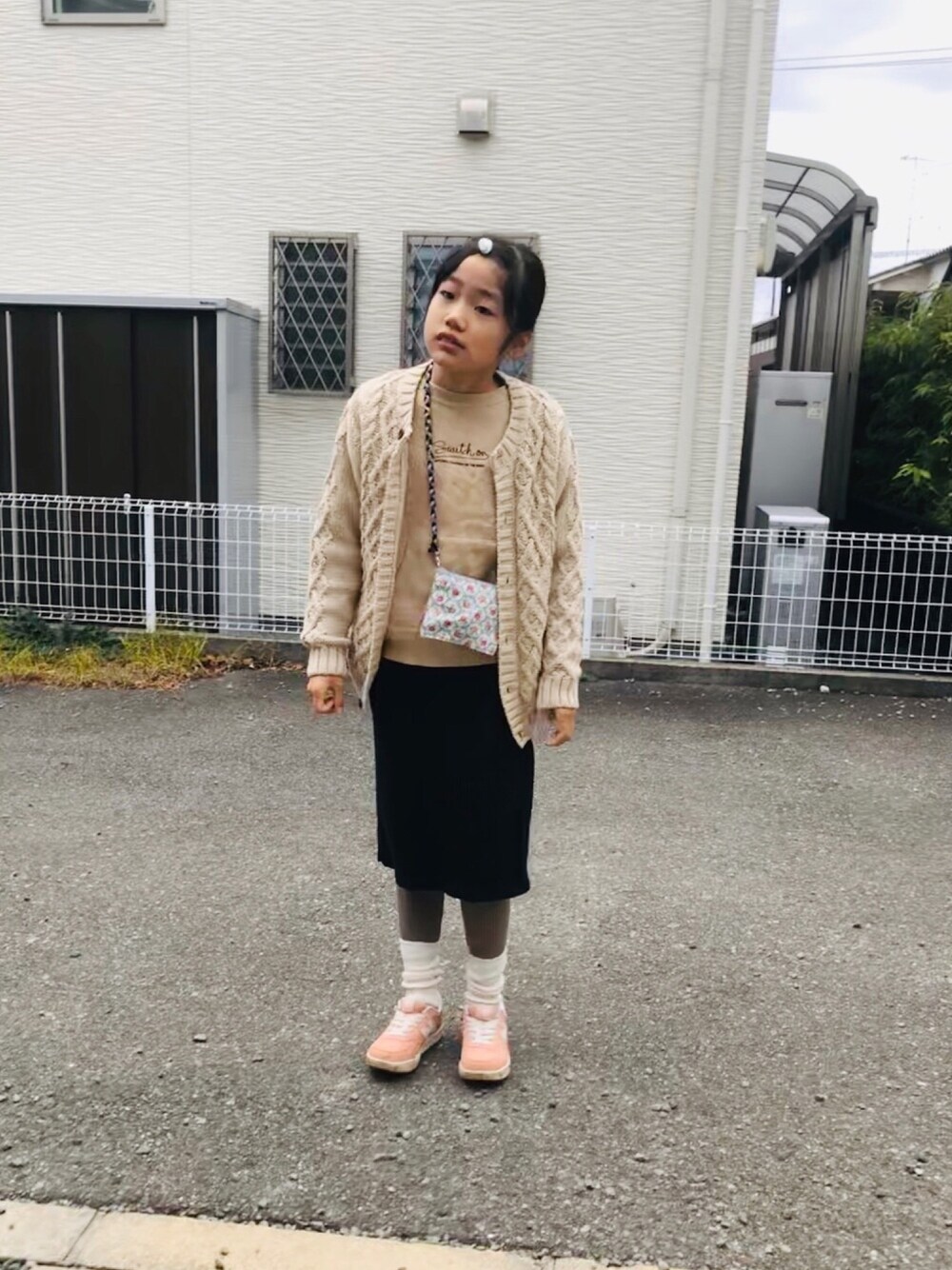 ベージュ系のスウェット、ブラック系のスカート、ピンク系のスニーカーを着用したキッズの秋コーディネートの1枚目の写真