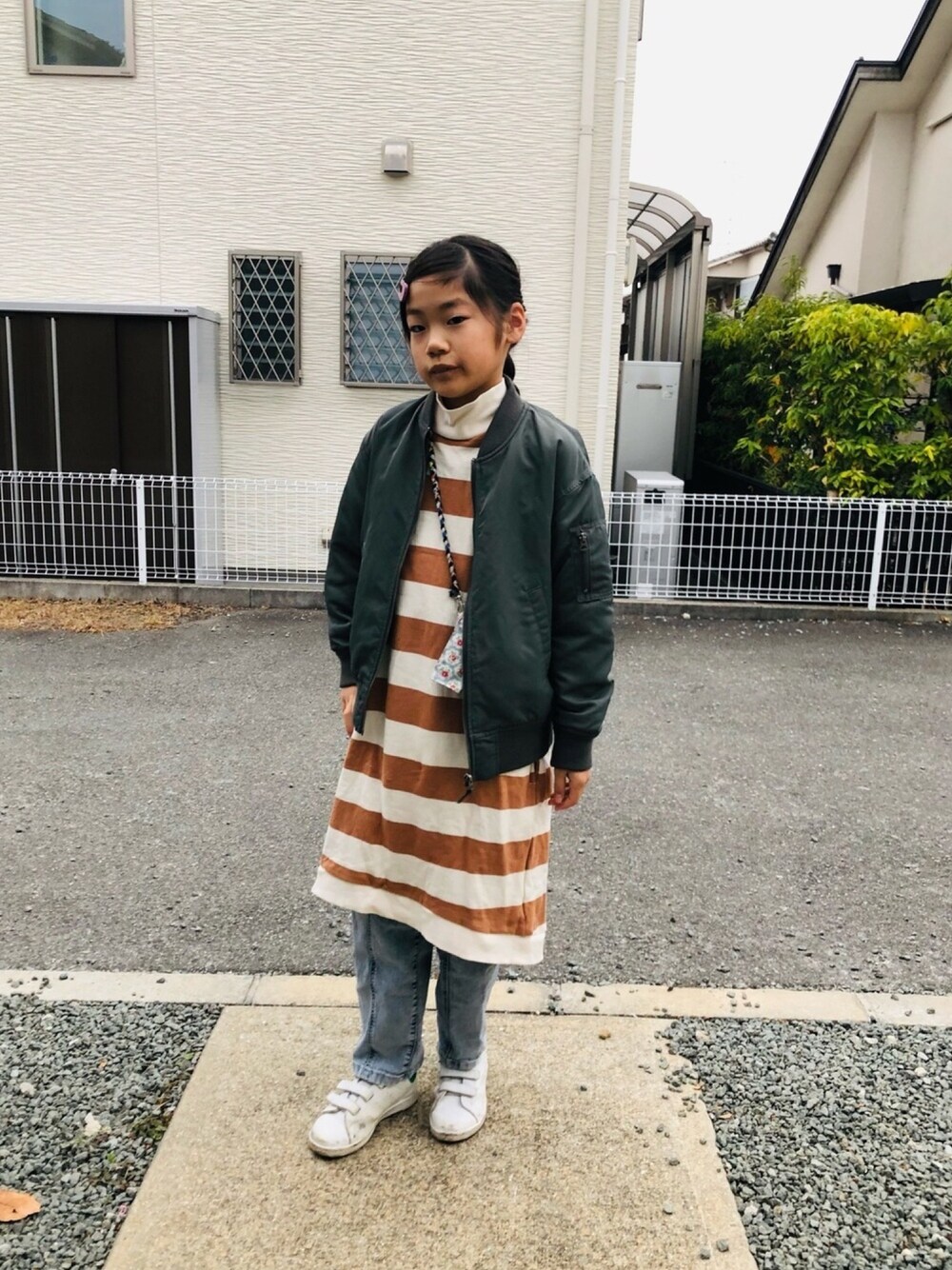 ブラウン系のワンピース、ホワイト系のスニーカー、パープル系のヘアピンを着用したキッズの冬コーディネートの1枚目の写真
