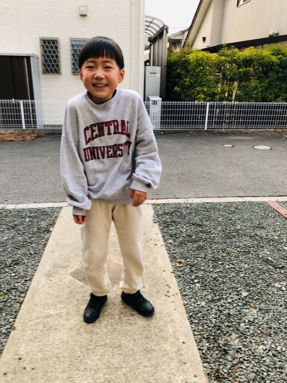 グレー系のスウェット、ブラック系のスニーカー、ホワイト系のその他パンツを着用したキッズの冬コーディネートの1枚目の写真