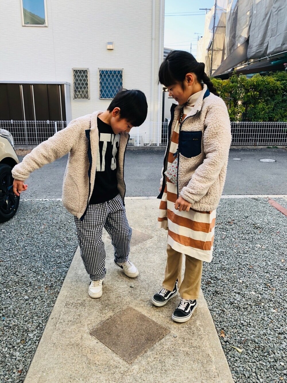 ブラック系のスウェット、ホワイト系のスニーカー、ブラウン系のワンピースを着用したキッズの春コーディネートの1枚目の写真