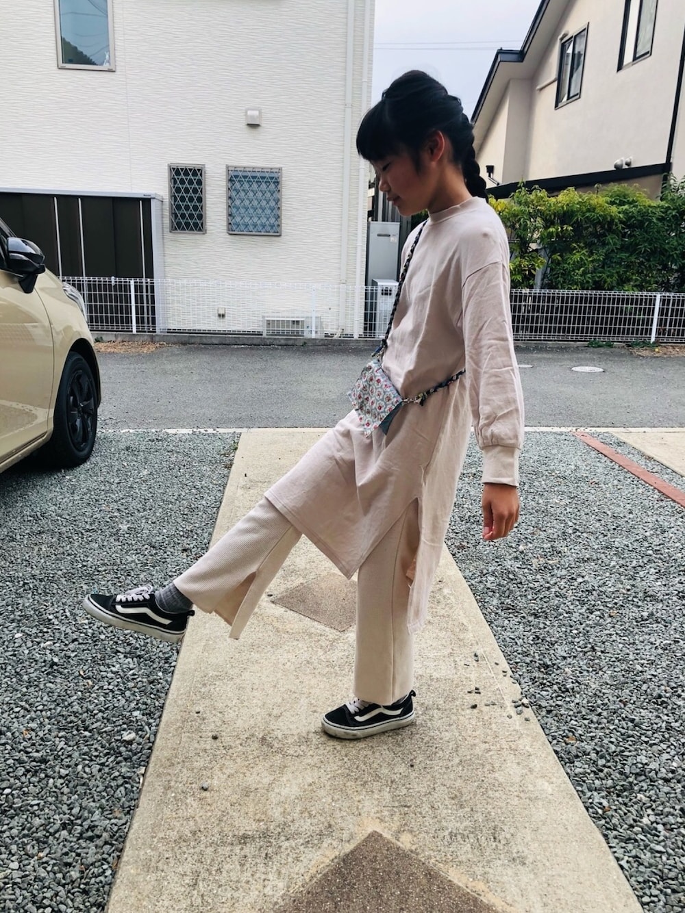 ベージュ系のワンピース、ベージュ系のその他パンツ、ブラック系のスニーカーを着用したキッズの春コーディネートの1枚目の写真