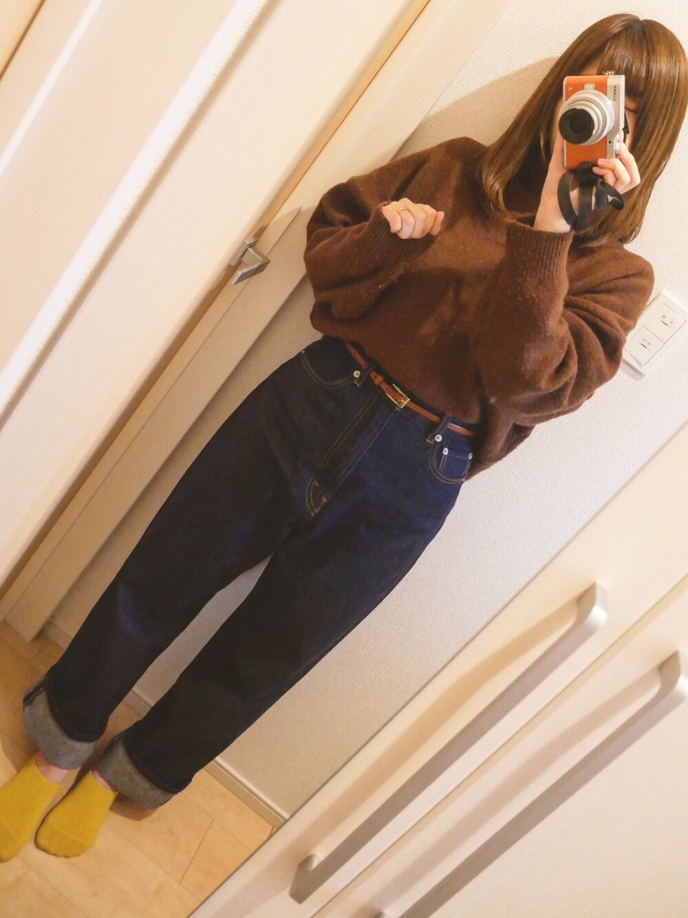 ブルー系のデニムパンツ、ブラウン系のニット/セーター、ブラウン系のアナログ腕時計を着用したレディースの秋コーディネートの1枚目の写真