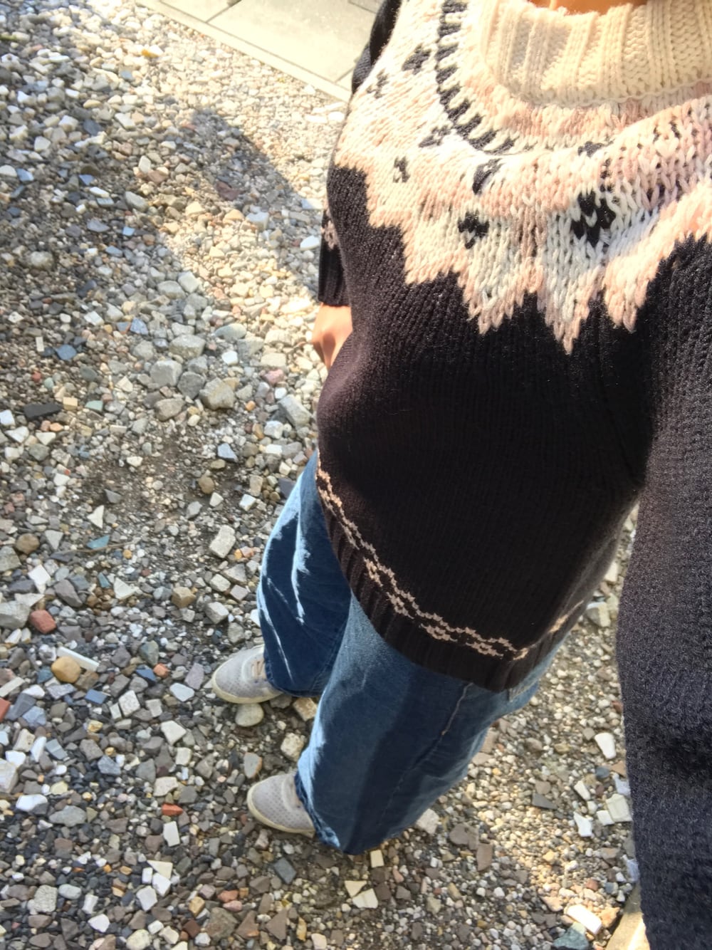 ブルー系のデニムパンツ、ブラック系のニット/セーター、パープル系のスニーカーを着用したレディースの冬コーディネートの1枚目の写真