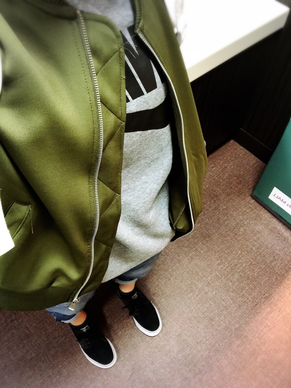 グレー系のスウェット、グリーン系のジャケット/アウター、ブラック系のスニーカーを着用したレディースの冬コーディネートの1枚目の写真