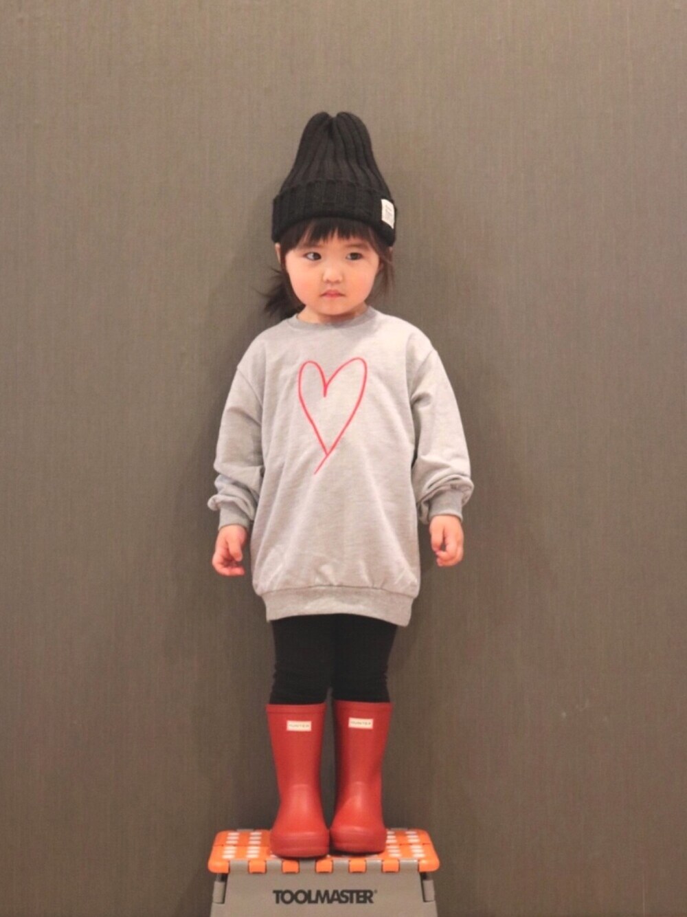 グレー系のスウェット、レッド系のレインシューズ、ブラック系のニットキャップ/ビーニーを着用したキッズの秋コーディネートの1枚目の写真