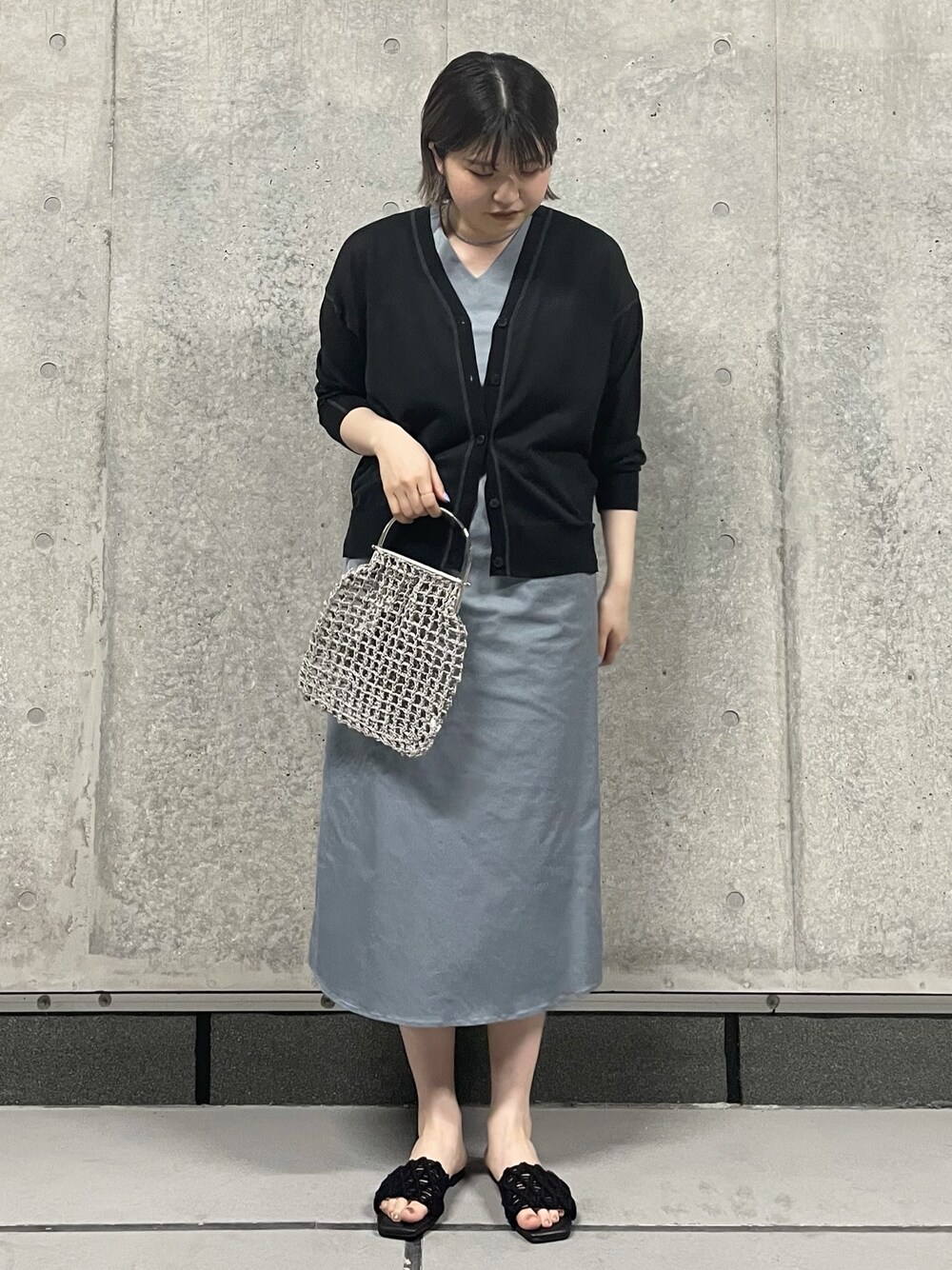 ベージュ系のハンドバッグ、グレー系のワンピース、ブラック系のサンダルを着用したレディースの夏コーディネートの1枚目の写真