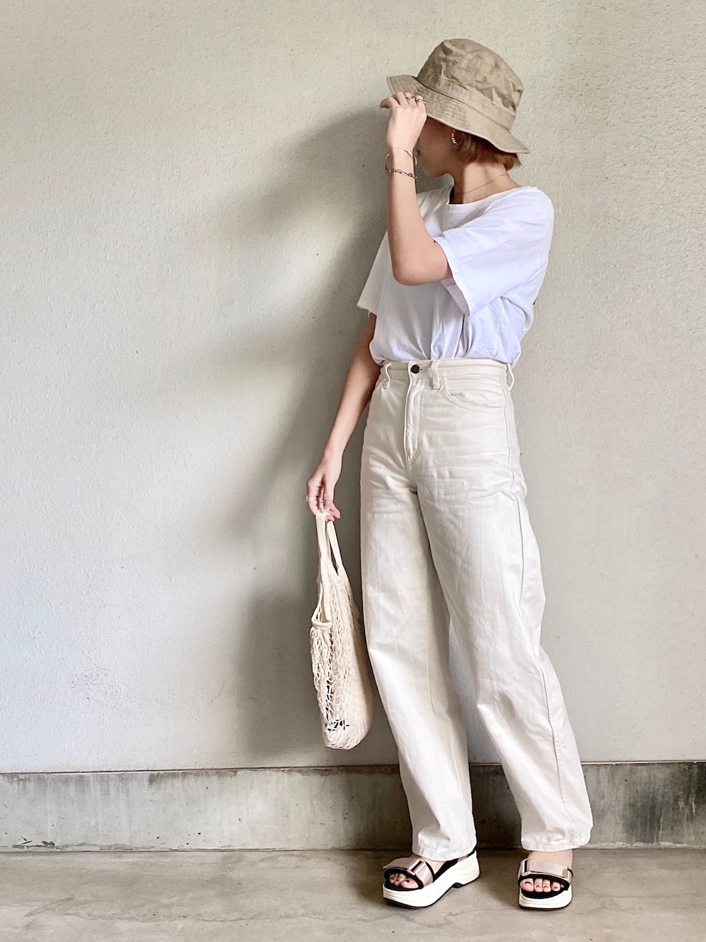 ホワイト系のデニムパンツ、ホワイト系のTシャツ/カットソー、ベージュ系のハットを着用したレディースの春コーディネートの1枚目の写真