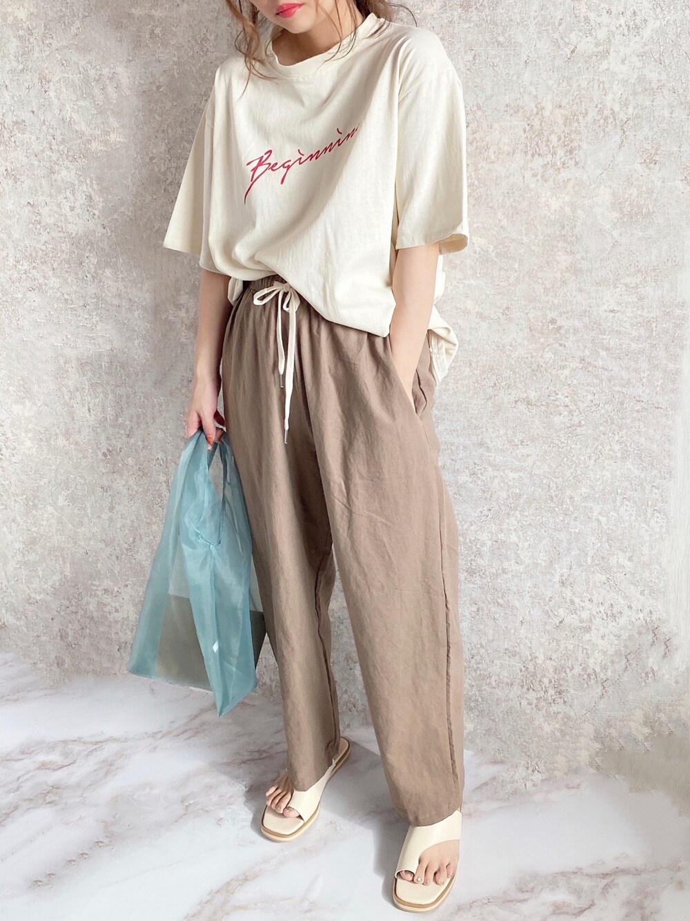 ベージュ系のTシャツ/カットソー、ブラウン系のその他パンツ、グリーン系のエコバッグ/サブバッグを着用したレディースの夏コーディネートの1枚目の写真