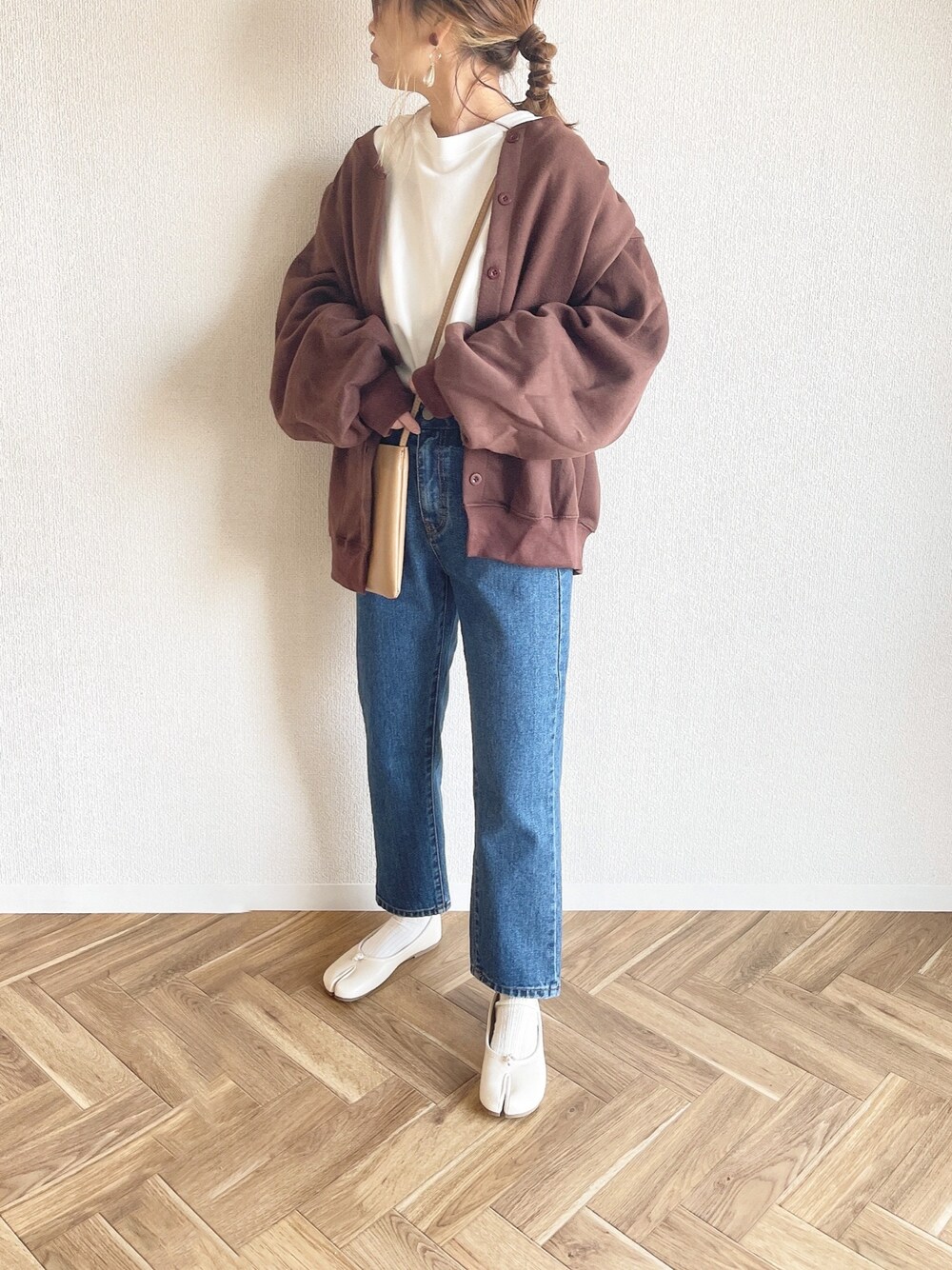 ブルー系のデニムパンツ、ベージュ系のショルダーバッグ、ホワイト系のその他を着用したレディースの冬コーディネートの1枚目の写真