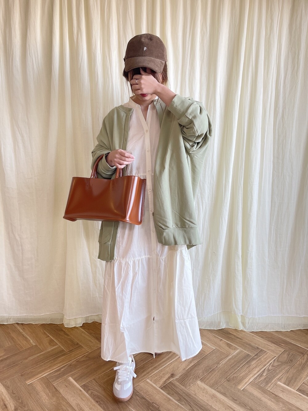 ホワイト系のワンピース、グリーン系のカーディガン/ボレロ、ブラウン系のバッグを着用したレディースの春コーディネートの1枚目の写真