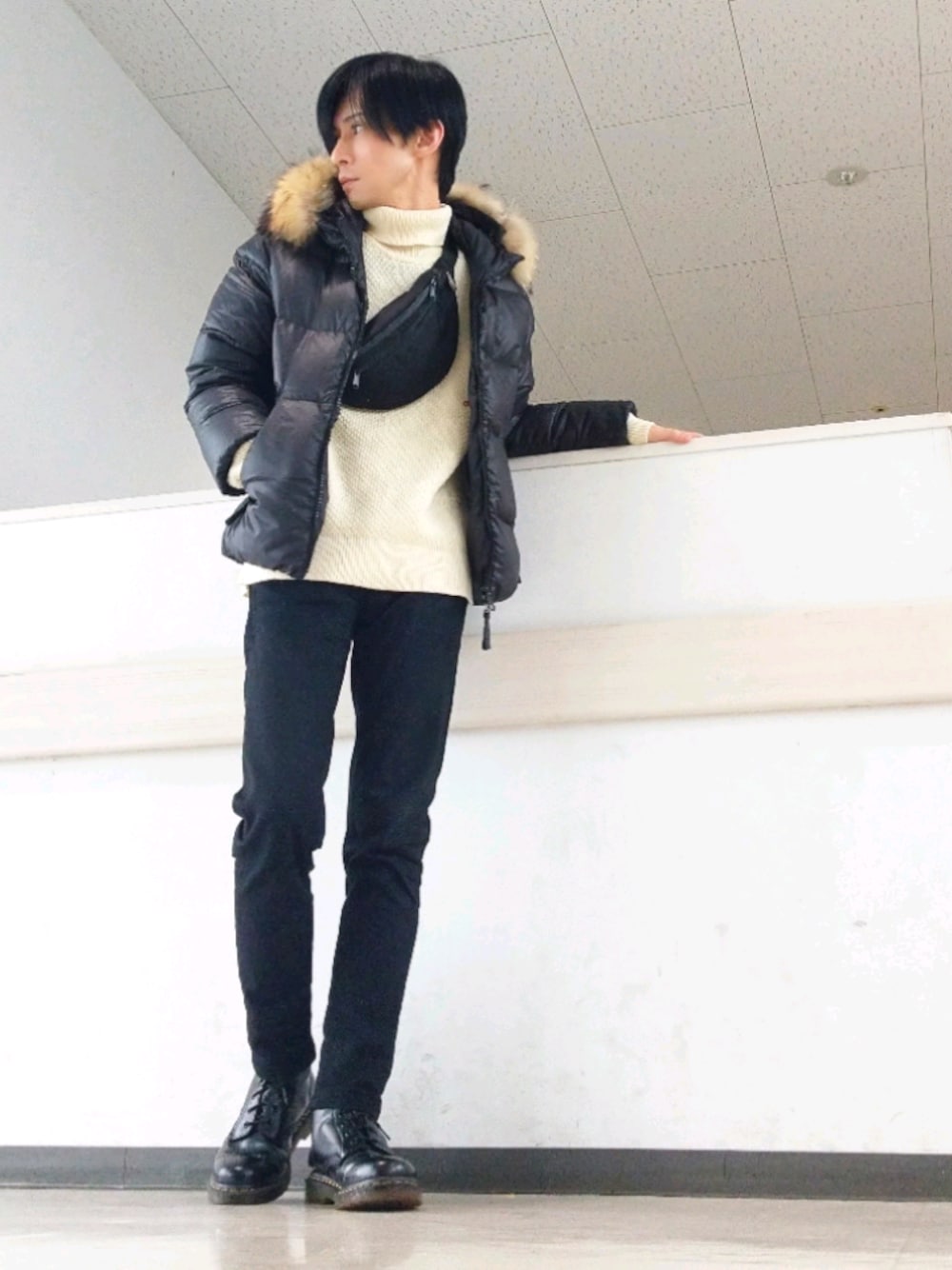 ブラック系のダウンジャケット/コート、ホワイト系のニット/セーター、ブラック系のデニムパンツを着用したメンズの冬コーディネートの1枚目の写真