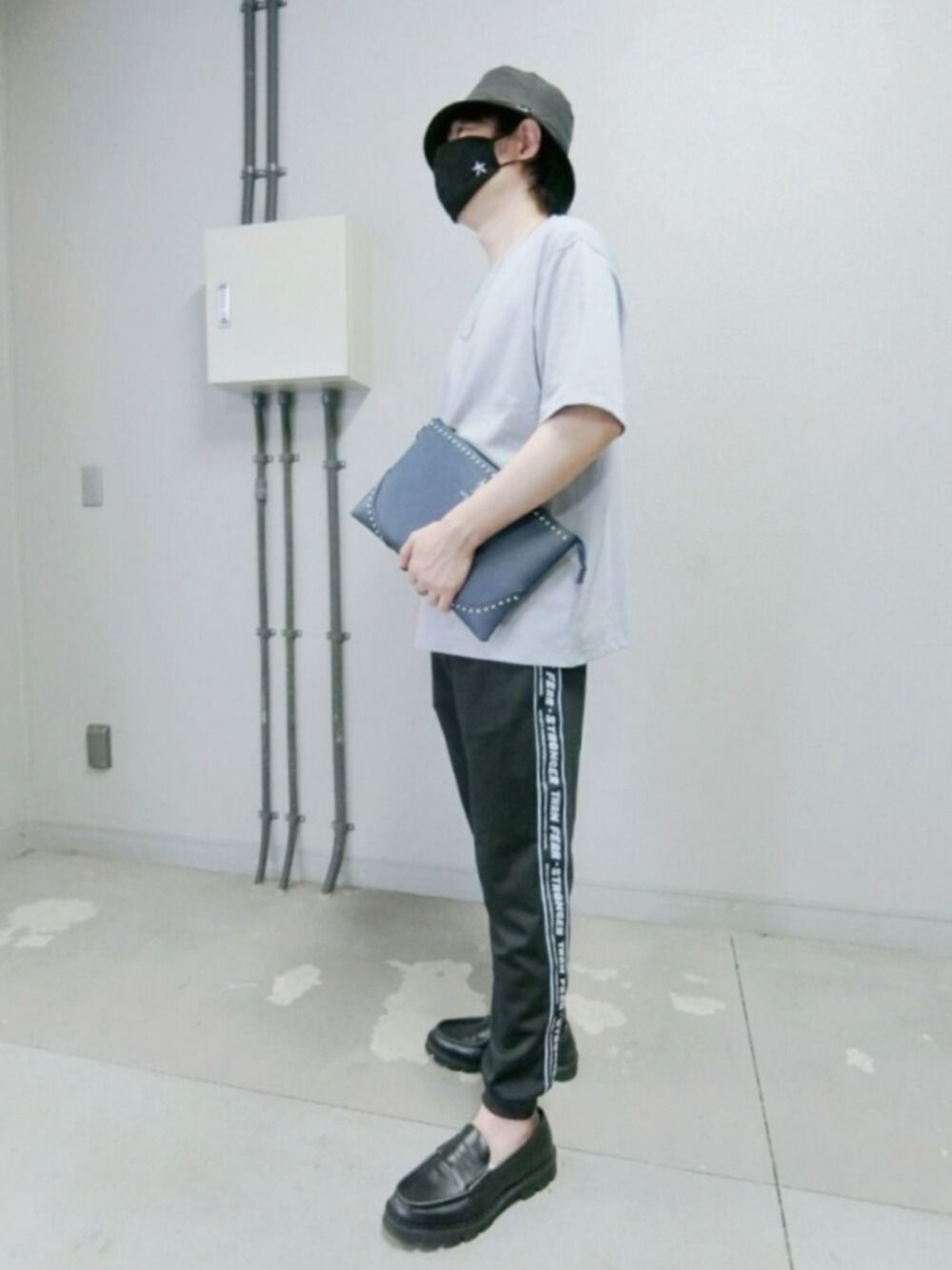 ブルー系のクラッチバッグ、ブルー系のTシャツ/カットソー、ブラック系のパンツを着用したメンズの夏コーディネートの1枚目の写真