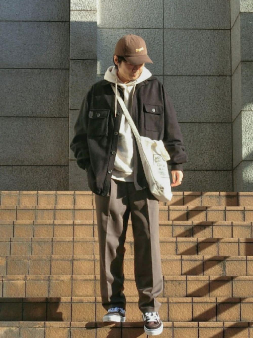 ブラウン系のスニーカー、ホワイト系のスウェット、ホワイト系のトートバッグを着用したメンズの冬コーディネートの1枚目の写真