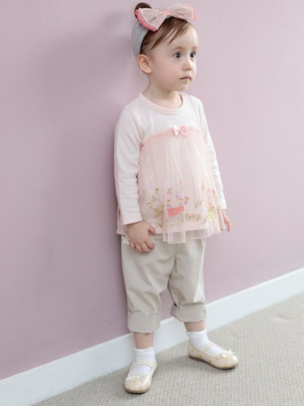 ピンク系のTシャツ/カットソー、ホワイト系のバレエシューズ、グレー系のヘアバンドを着用したキッズの冬コーディネートの1枚目の写真